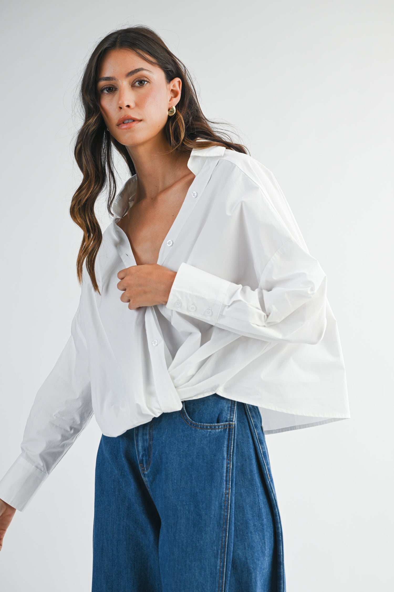 Woman wearing a white shirt and blue jeans on a plain background