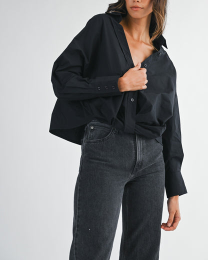 Woman wearing a black oversized shirt and dark jeans on a white background